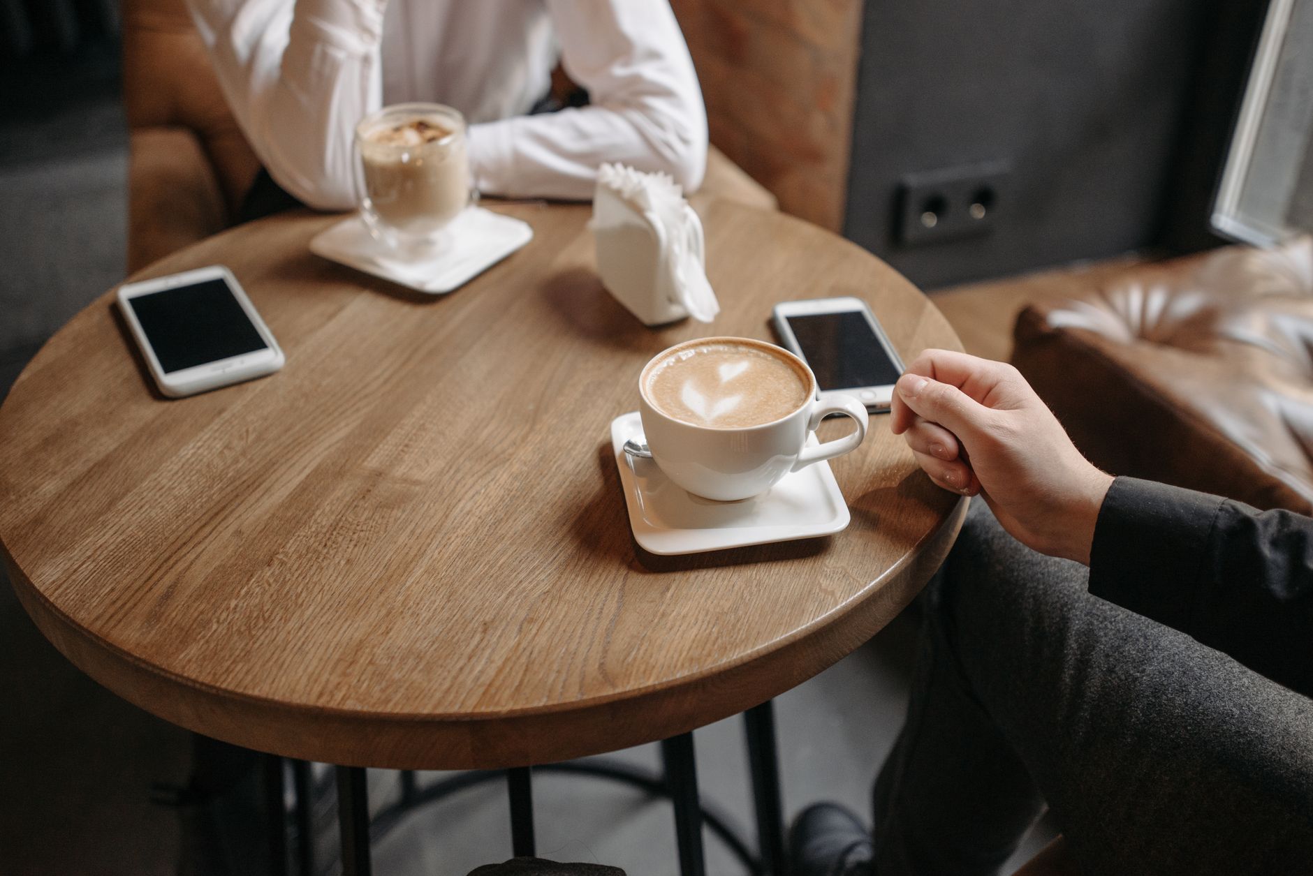 Twee mensen met koffie tegenover elkaar aan een cafétafel