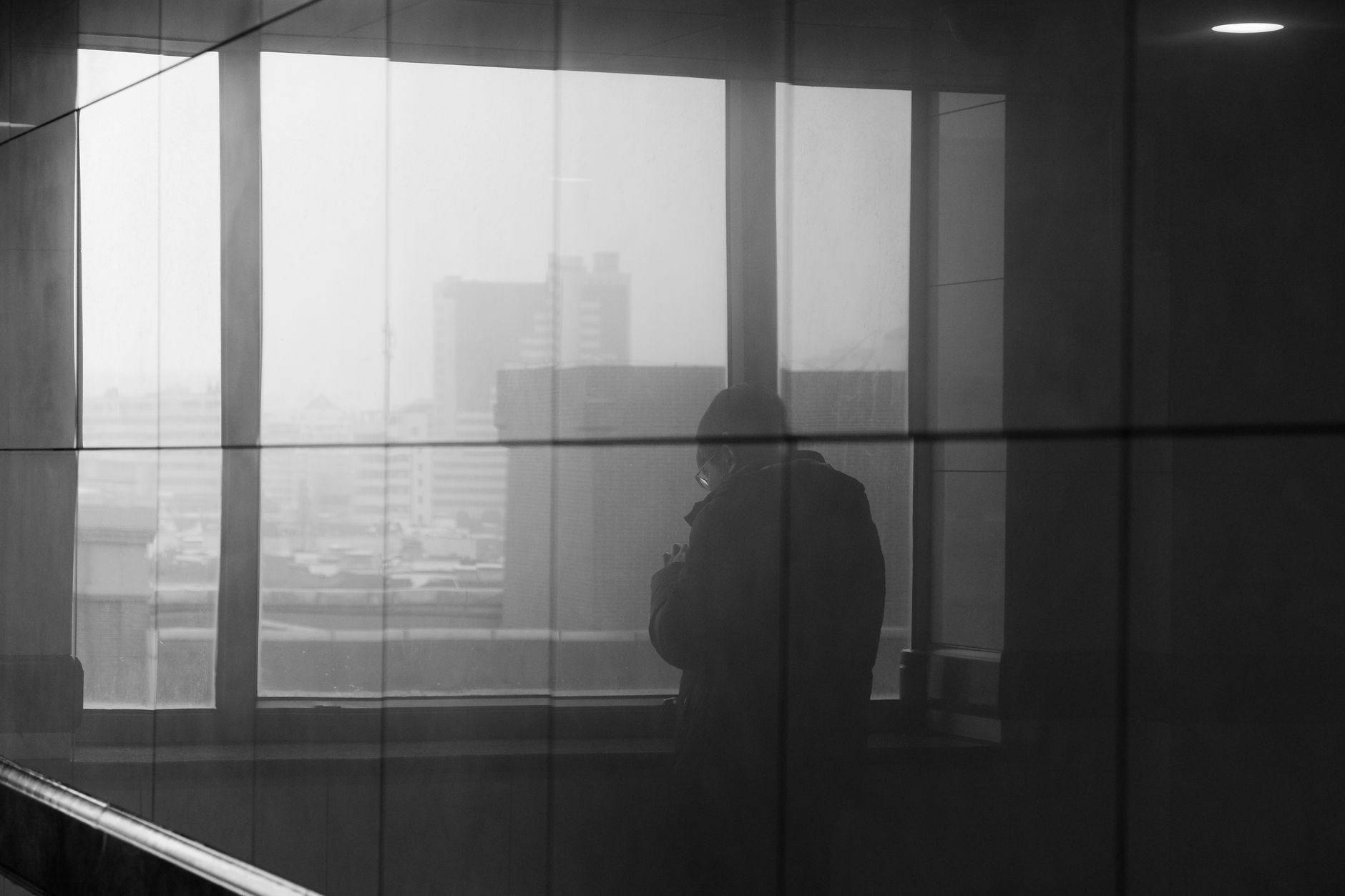 Silhouet van iemand bij een raam met uitzicht over de stad