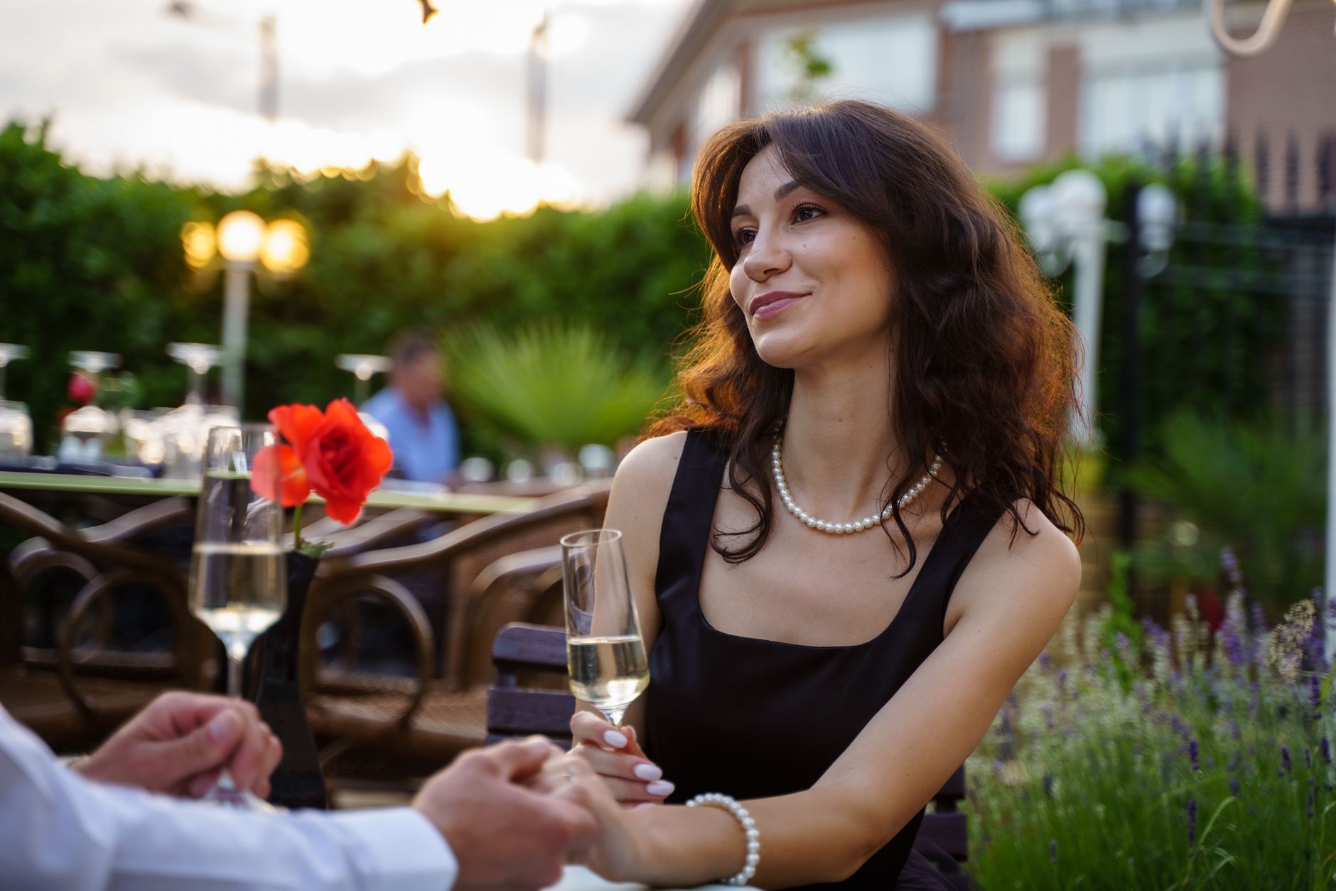 Lachende jonge vrouw met een glas op een terras bij zonsondergang