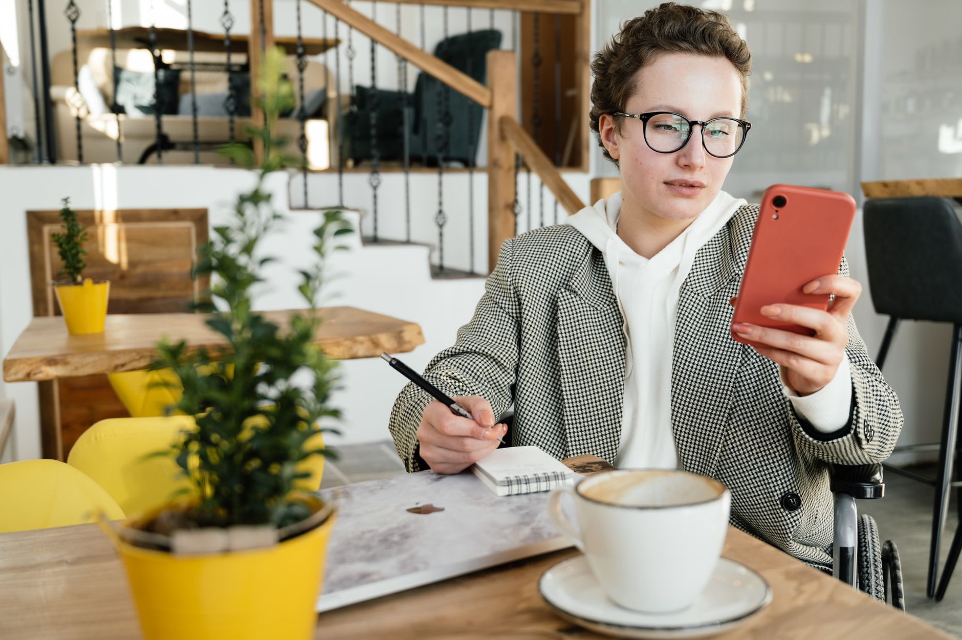 Vrouw met bril werkt geconcentreerd op een telefoon en tablet